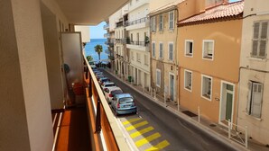 A balcony with a view of a street lined with parked cars and buildings. - Apartment very close to the sea (Toulon)