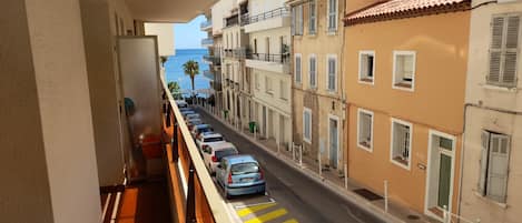 A balcony with a view of a street lined with parked cars and buildings.