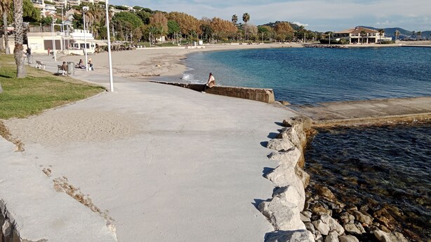 A coastal walkway with a concrete path, a rocky shoreline, and a beach in the background. - Apartment very close to the sea (Toulon)