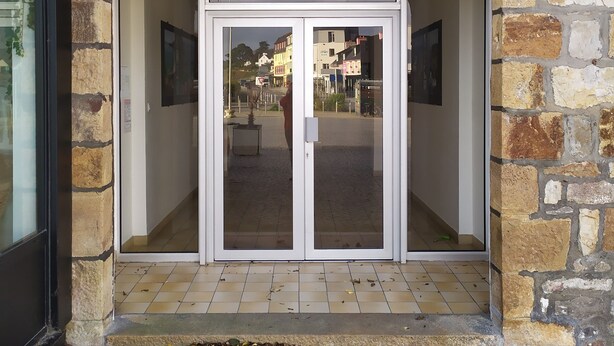 A stone archway leading to a glass door entrance. - Apartment (Crozon)