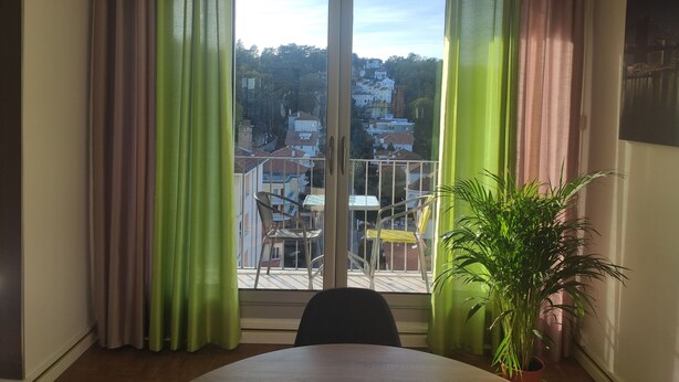 Een kamer met balkon, een tafel en een bloempot.