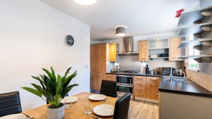 Una cucina moderna con mobili in legno, elettrodomestici in acciaio inossidabile e un'area pranzo con un tavolo apparecchiato per due.