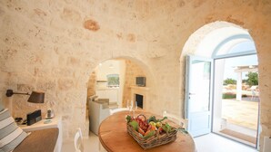 A rustic stone interior with a wooden table and a fruit basket. - TD Lamiamola Stylish Trulli Lamie With Pool (Ostuni)