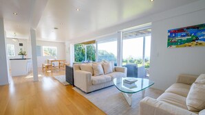 Una sala de estar moderna con un sofá, una mesa de centro de vidrio y vistas al exterior.
