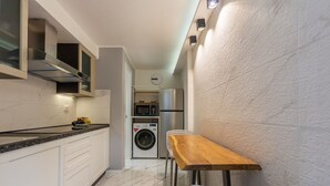 A compact kitchen with a washing machine, a microwave, and a refrigerator.
