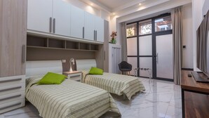 A modern bedroom with two beds, a desk, and a chair.