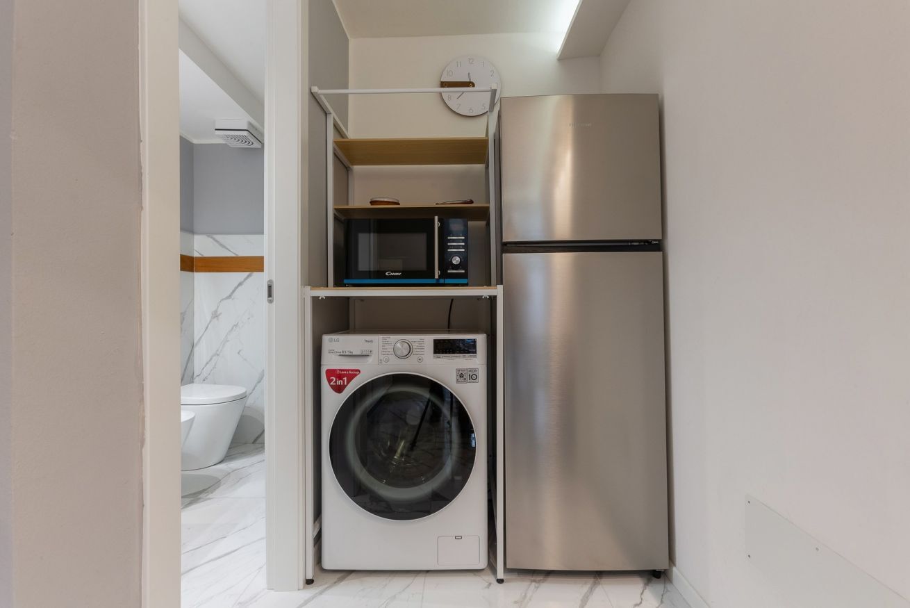 Une cuisine compacte équipée d’un lave-linge, d’un four à micro-ondes et d’un réfrigérateur.