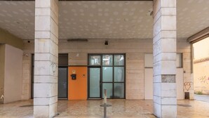 A building entrance with a tiled floor, a glass door, and a small orange sign.