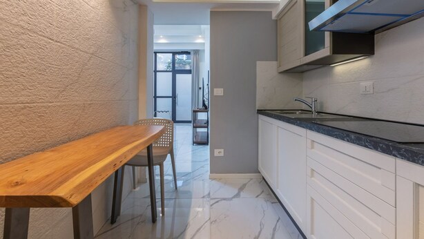 A modern kitchen with white cabinetry, a built-in microwave, and a marble floor.