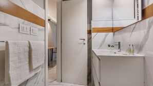 A modern bathroom with a marble floor, a white sink, and a wooden accent wall.