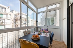 Un balcon avec une table à manger, des chaises et un saladier rempli d’oranges.