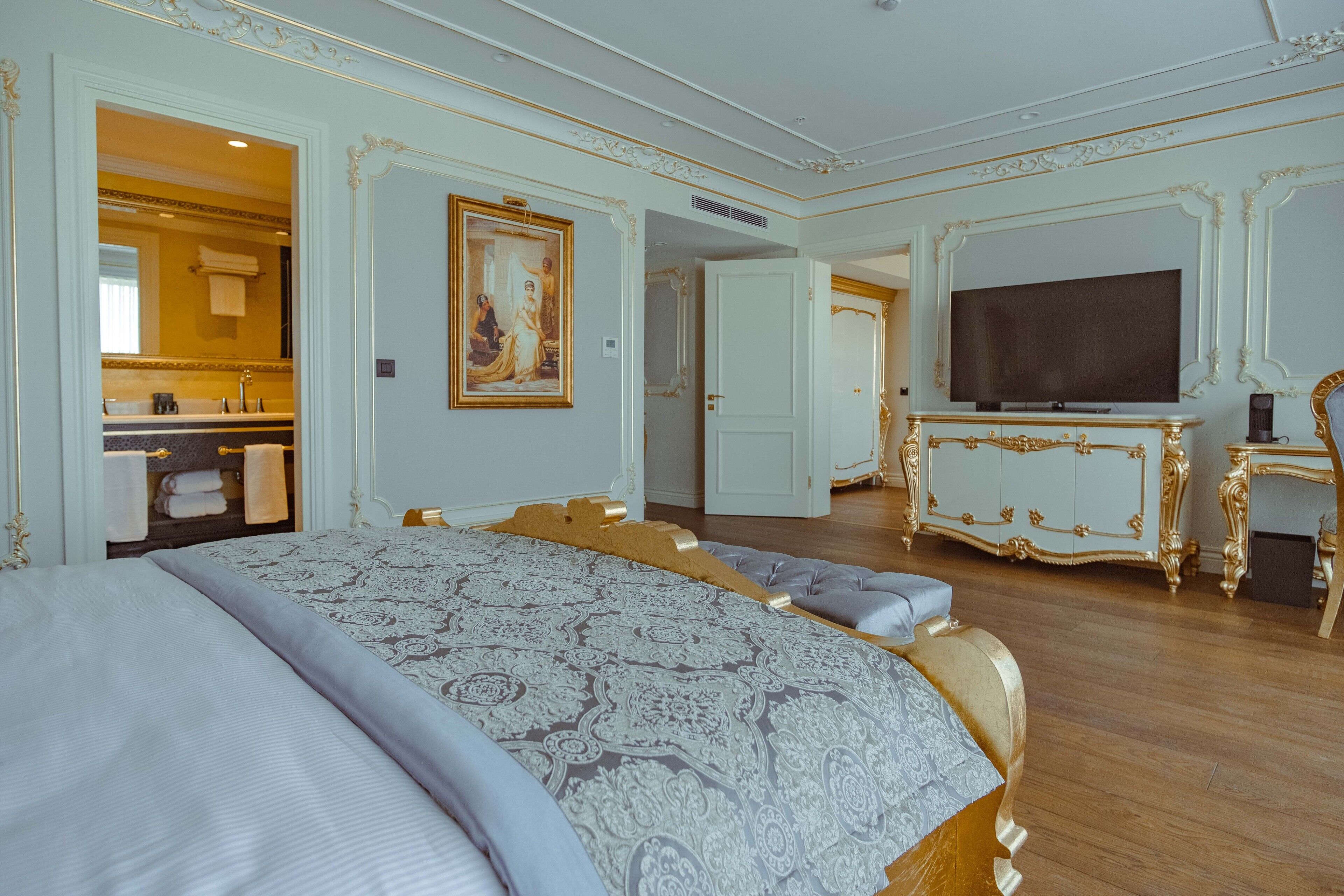 Une chambre spacieuse avec un grand lit, une télévision et une salle de bain visible à travers une porte ouverte.