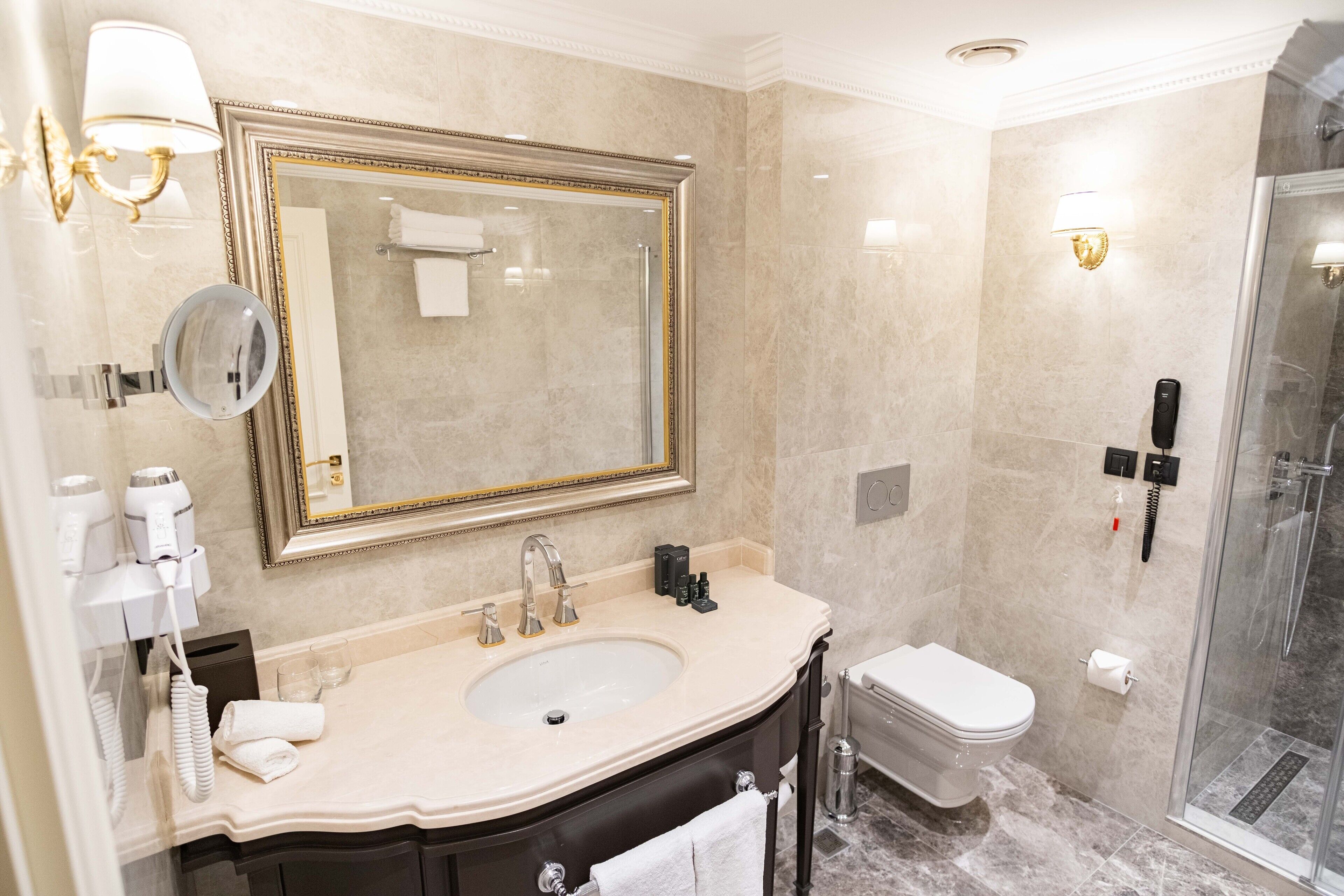 Een badkamer met een grote spiegel, een wastafel, toilet en douche.