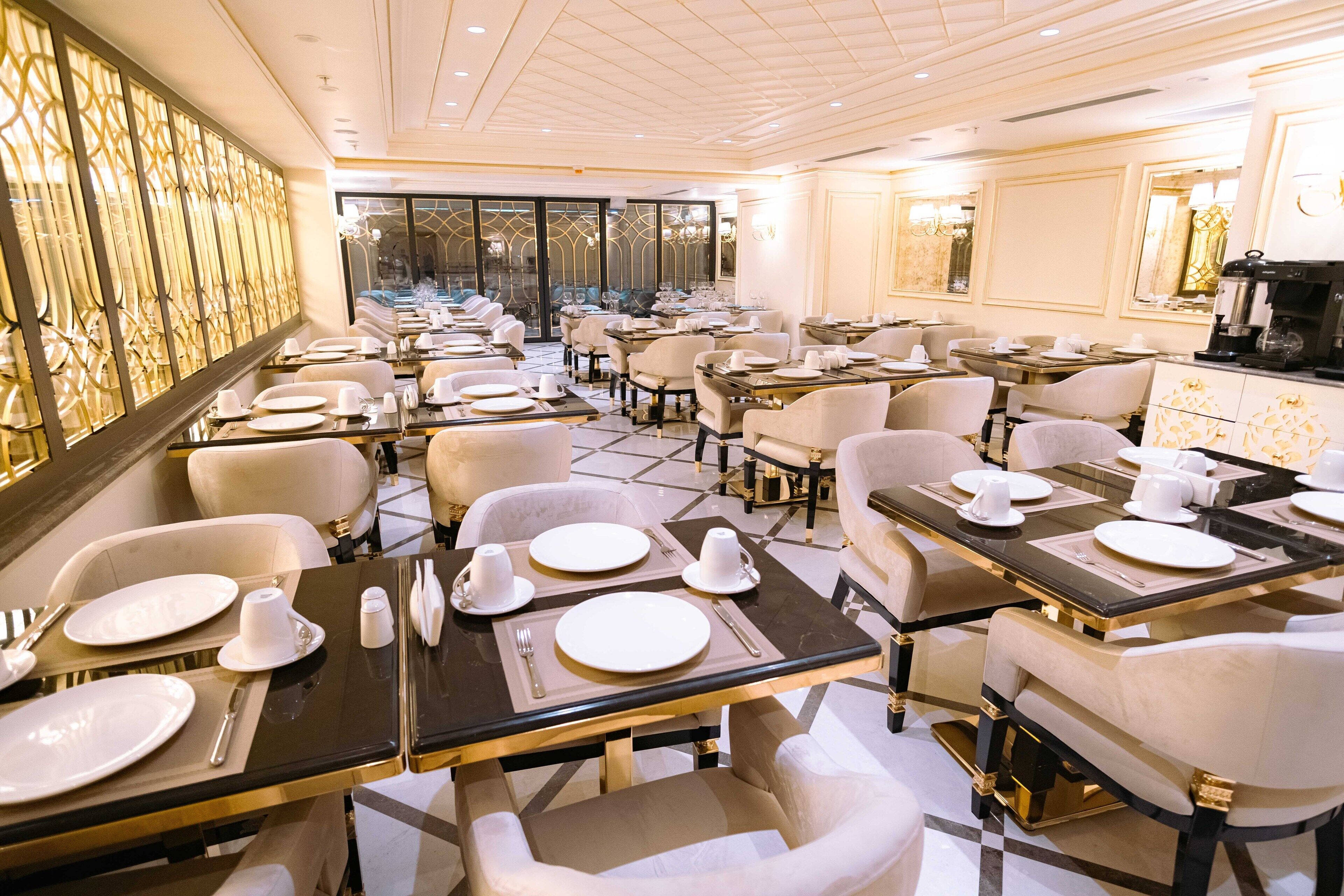 Een ruim restaurant met meerdere tafels gedekt, met stijlvolle stoelen en een modern interieur.