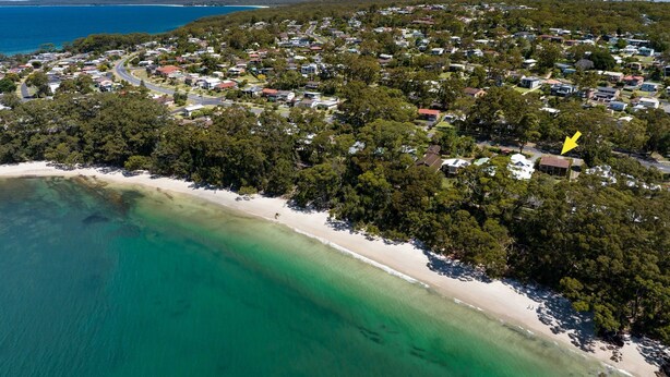 Luchtbeeld van een kustplaatsje met een strand, huizen en een weg.