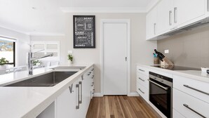 Een moderne keuken met witte kastjes, een roestvrijstalen spoelbak en een zwarte achterwand.