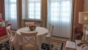 A dining area with a round table, white chairs, a bowl of fruit, and a lamp. - PORTO CLÉRIGOS Apartments Daisy (1st) (Porto)