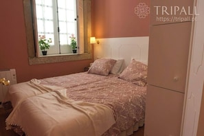Un dormitorio con dos camas, una ventana con vistas a flores y una lámpara de noche.