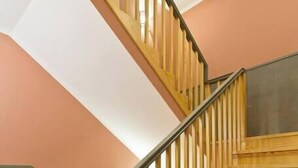 A wooden staircase with a black handrail and a light-colored wall.