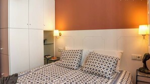 A bedroom with a bed, two bedside lamps, a wardrobe, and a nightstand with a lamp.