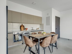A modern kitchen with a dining area. It includes a stove, oven, sink, and a dining table with chairs.