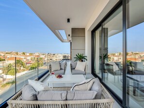 Un balcon avec un canapé, une table et un pot de fleurs.