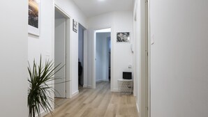 A hallway with wooden flooring, white walls, and a potted plant. - AdAstra b&b (Naples)