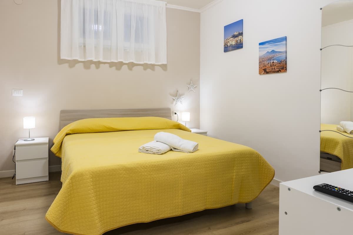 A hotel room with a bed, a nightstand, a bedside lamp, and a mirror.