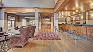 Un hall d’entrée avec un comptoir de réception, des lambris en bois, un tapis à motifs et un espace salon.