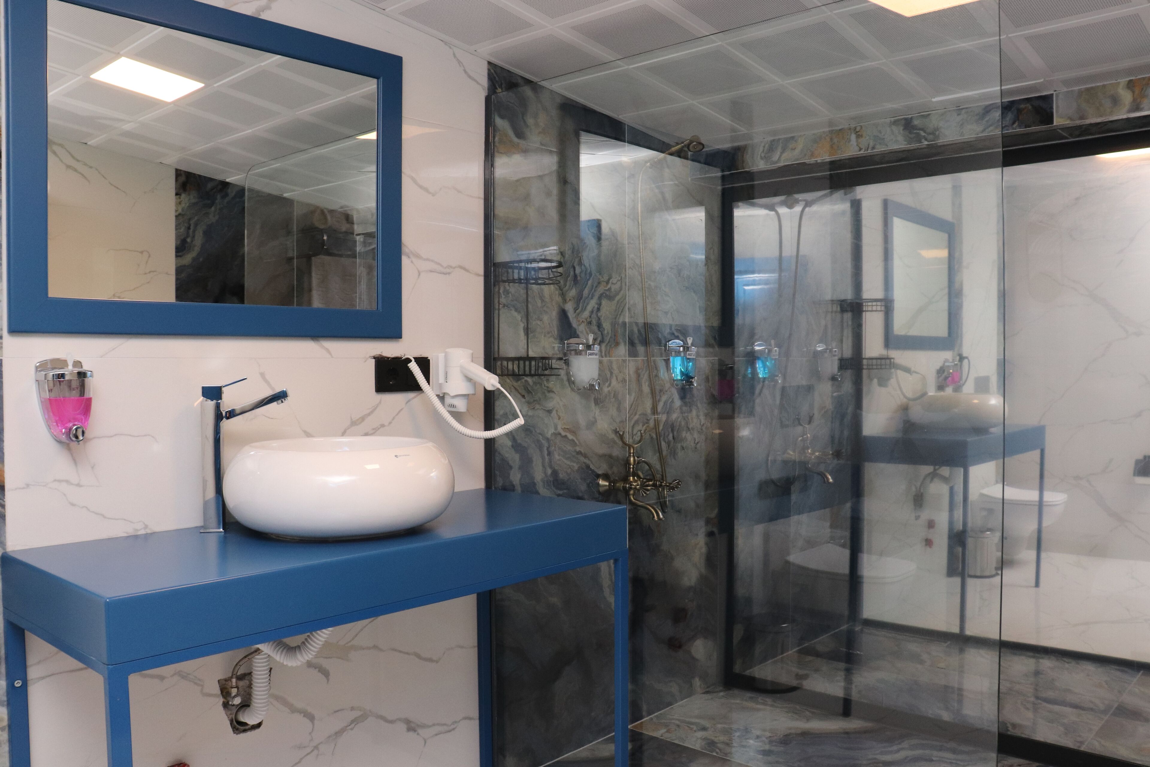 Une salle de bain moderne avec un meuble-lavabo bleu, un évier blanc et une cabine de douche en verre.