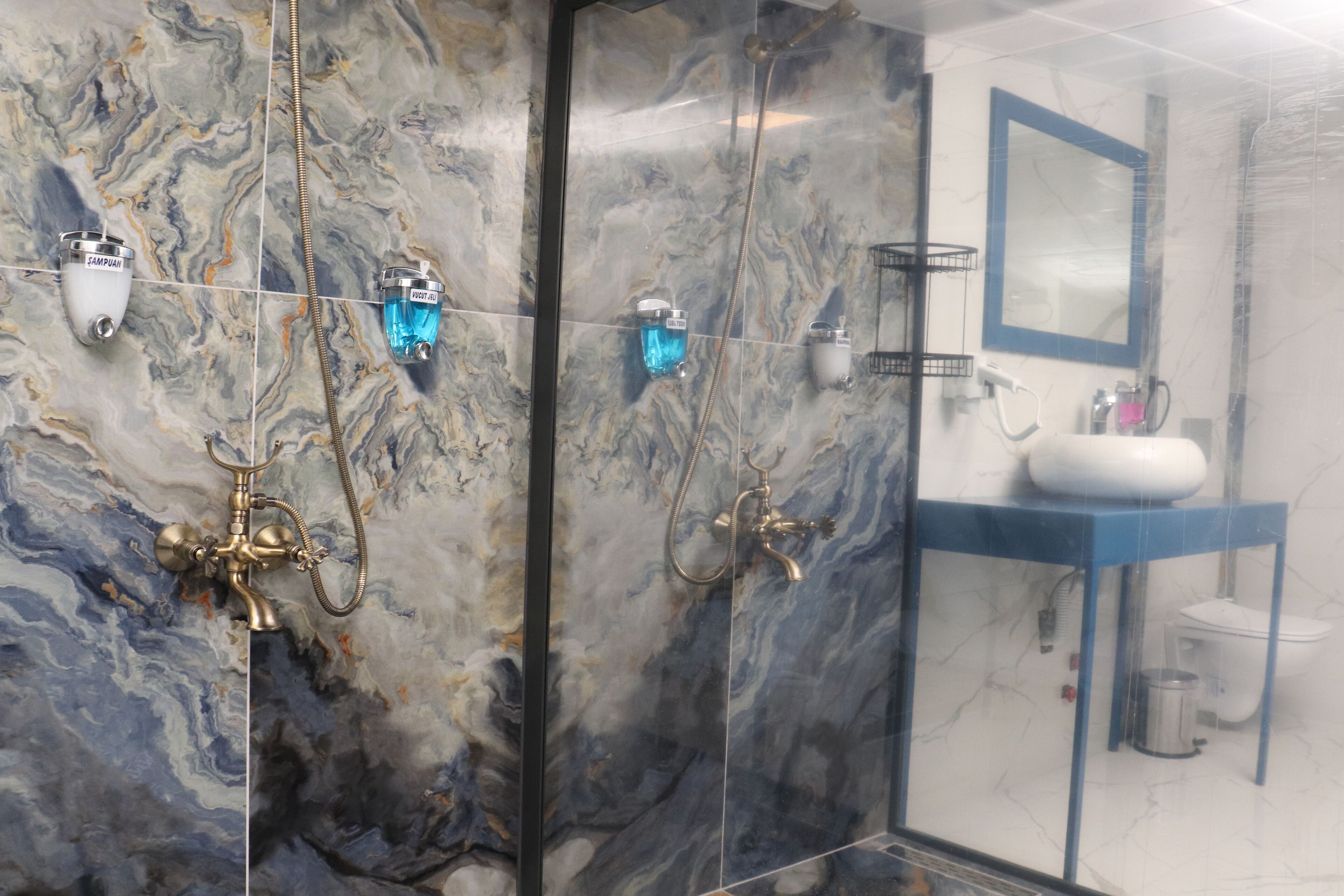 A bathroom with marble walls, a blue sink, and a mirror.