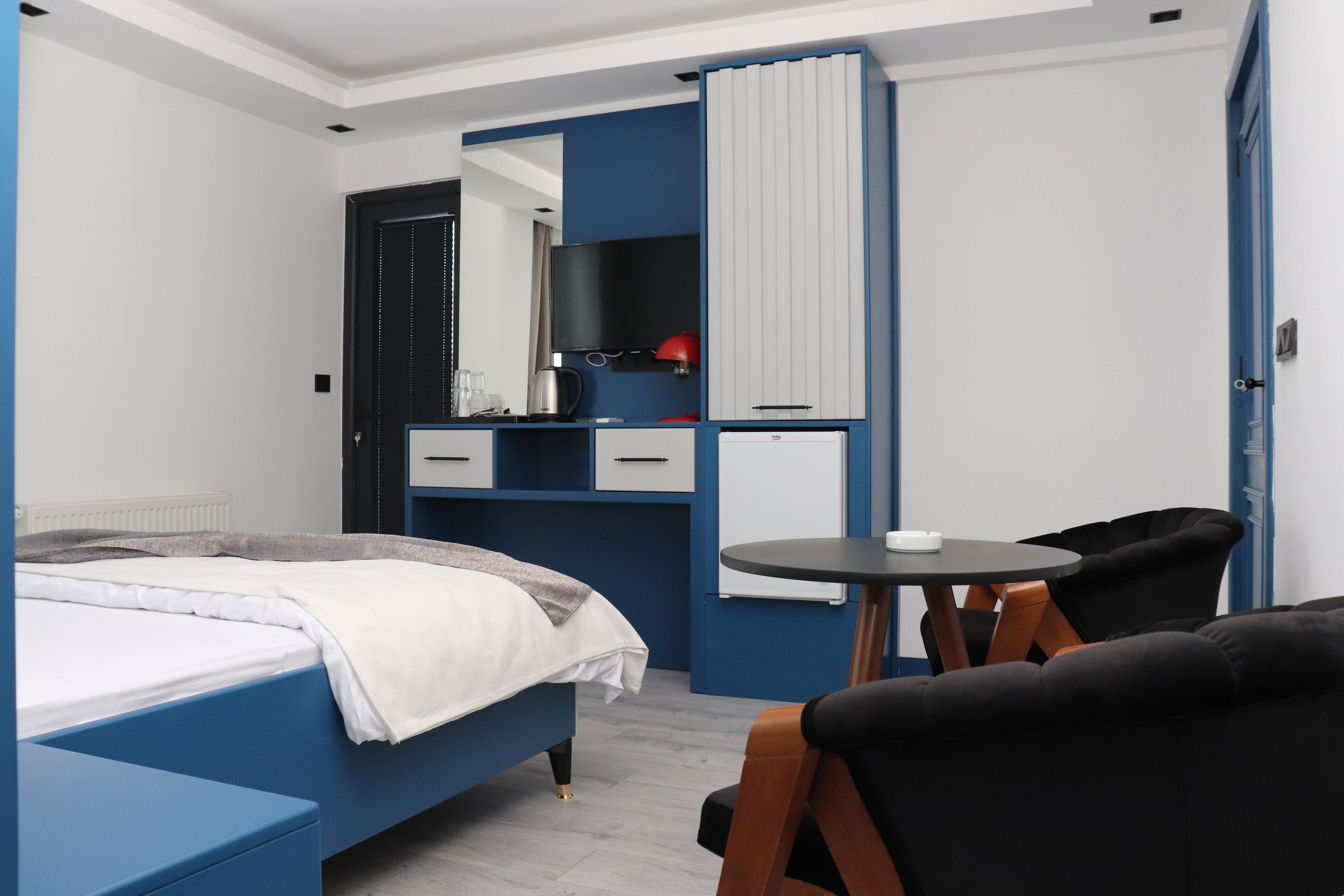 Un dormitorio moderno con una cama, un escritorio, una silla y un televisor.