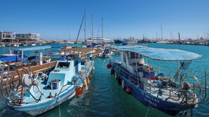 A marina with various boats docked, a building with a sign, and a clear blue sky. - Sanders Elgio - Charming Studio With Balcony (Limassol)