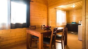 A wooden cabin interior with a dining table and chairs, a kitchen area with cabinets and appliances, and a window with curtains. - 2 bedroom private vacation home in figueirã³ dos vinhos (Figueiró dos Vinhos)