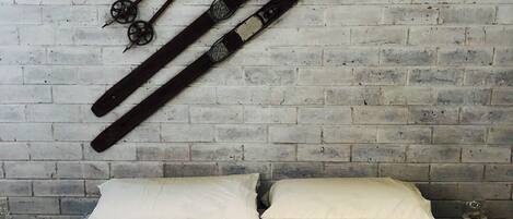 A bed with a leopard print bedspread and two white pillows against a brick wall.