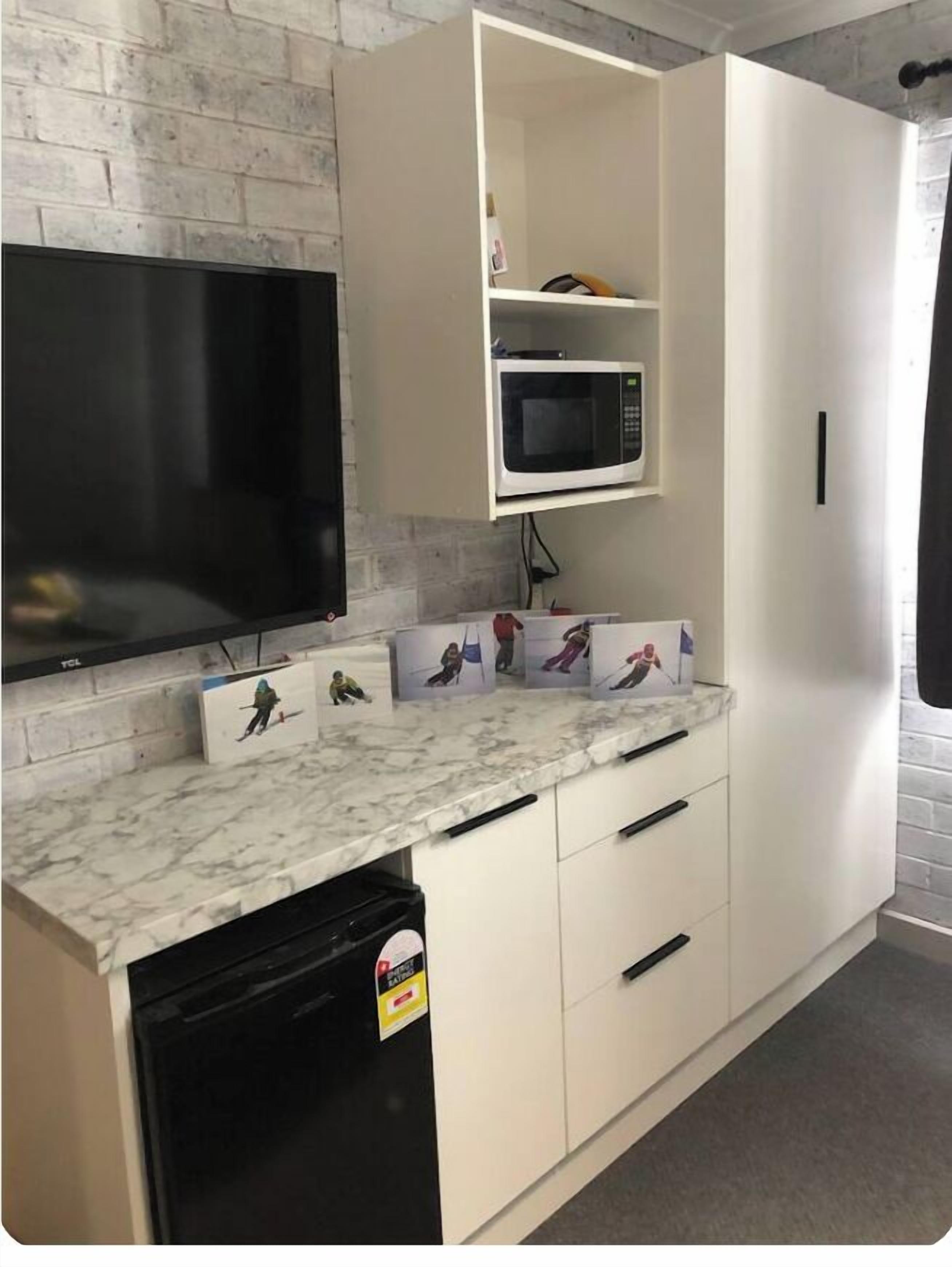 A kitchen with a TV, microwave, and a dishwasher.