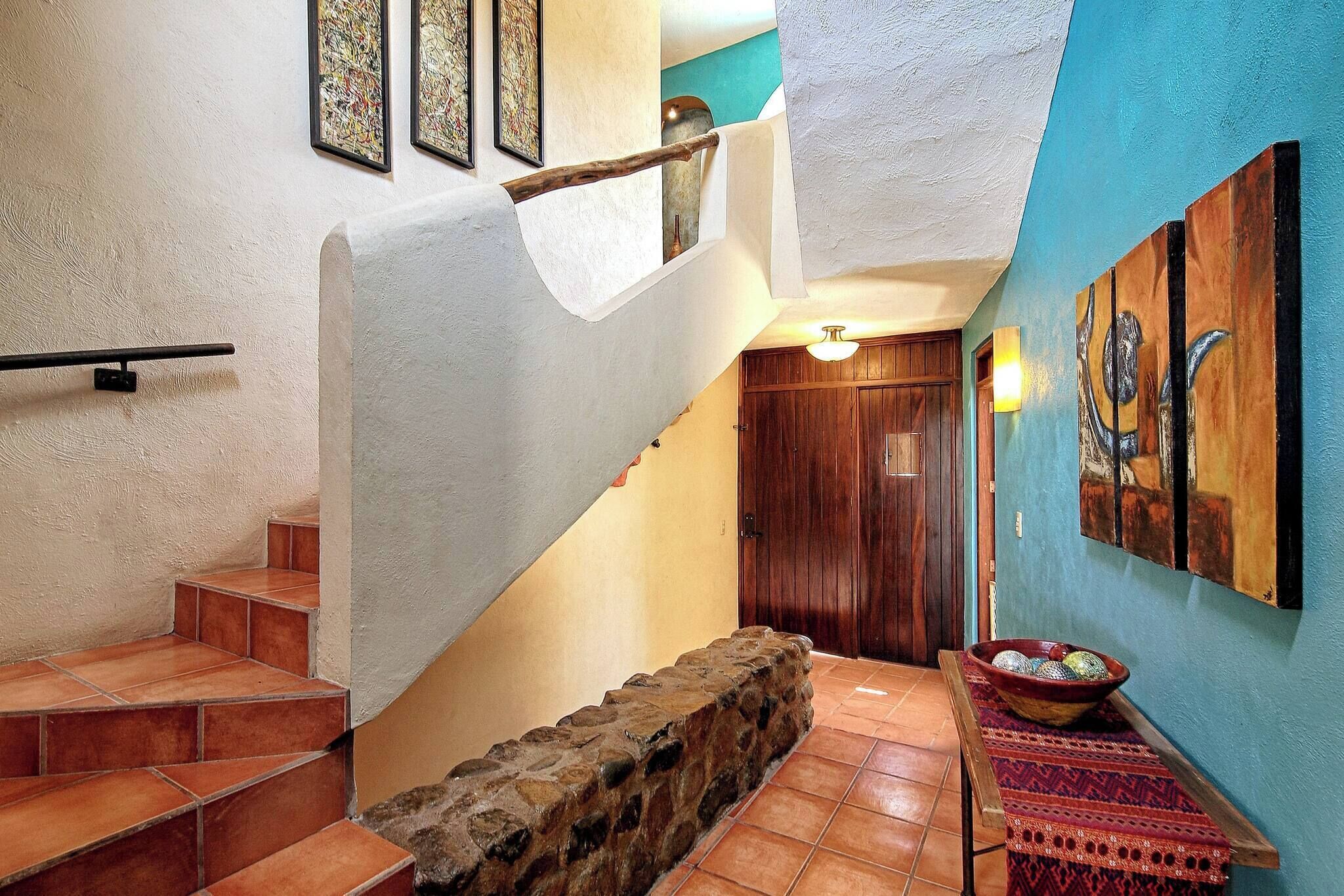 A staircase with a stone wall, a wooden door, and a wall-mounted artwork.