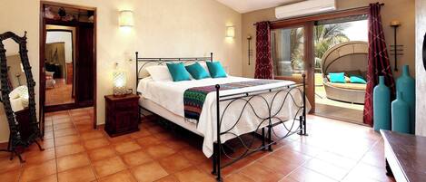 A bedroom with a bed, a ceiling fan, a nightstand, a mirror, and a view of the outside.
