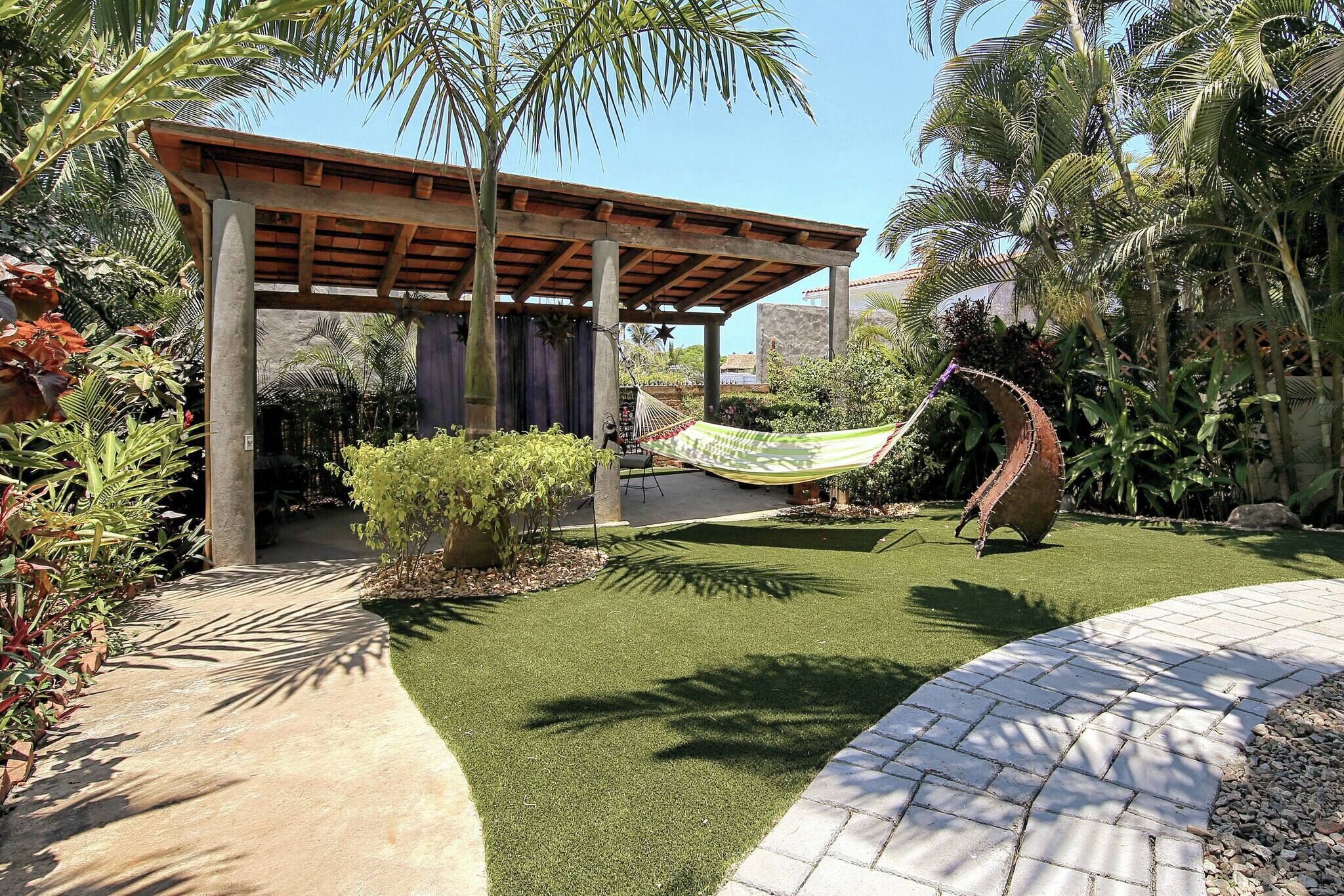 A garden with a hammock, a pergola, and a stone wall.