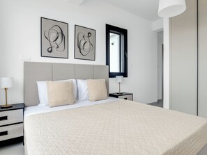 A modern bedroom with a large bed, a nightstand, a lamp, and abstract art on the wall.