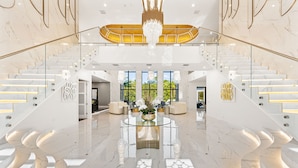 A grand lobby with a marble staircase, a chandelier, and a glass coffee table. - Grandhalla - the Pinnacle of Luxury in Orlando (Kissimmee)