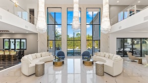 A spacious lobby with a white sofa set, two round coffee tables, and a large chandelier. - Grandhalla - the Pinnacle of Luxury in Orlando (Kissimmee)