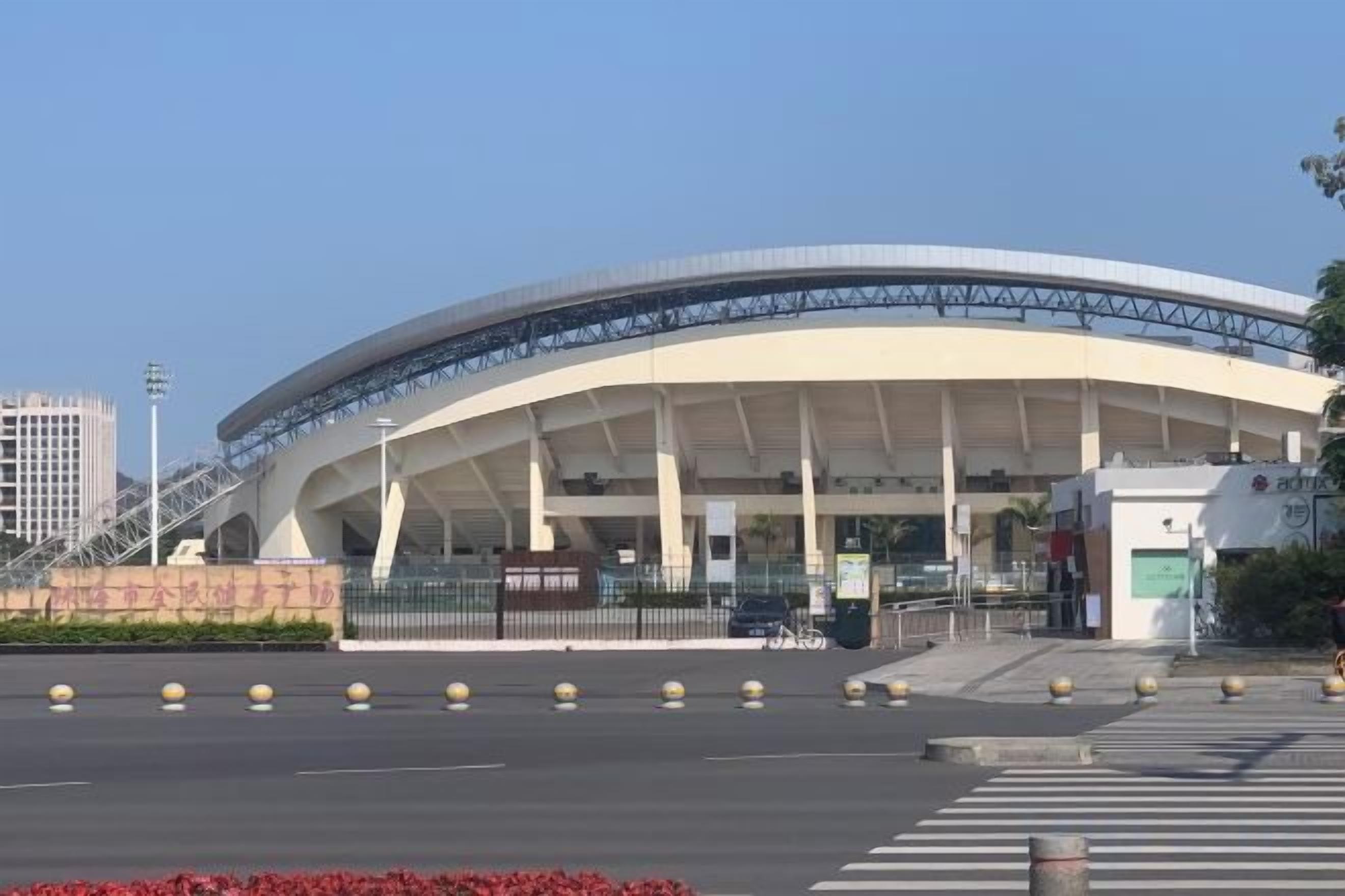 A large, modern stadium with a curved roof and multiple entry points.