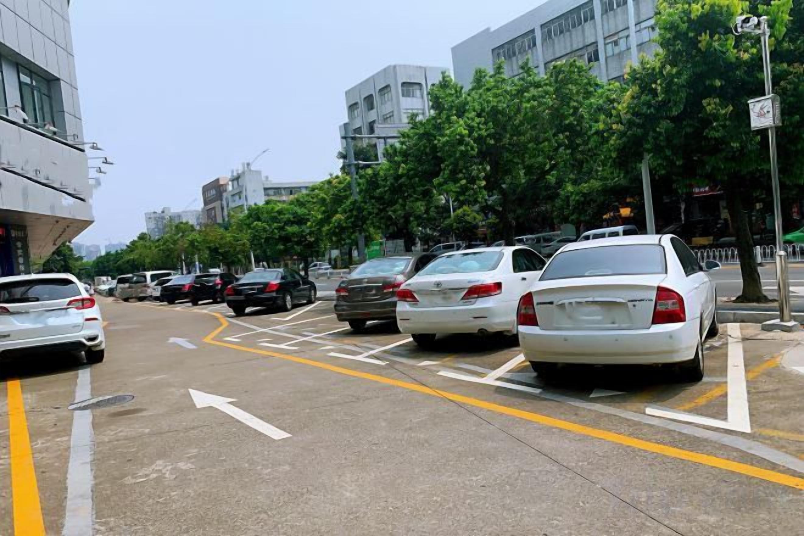 Eine Straße mit parkenden Autos und einem Gebäude im Hintergrund.