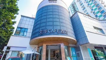 Een modern gebouw met een gebogen gevel en een bord waarop staat '文华CAFE酒店'.