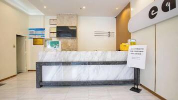 A reception desk with a marble top, a wall-mounted television, and a sign with text.