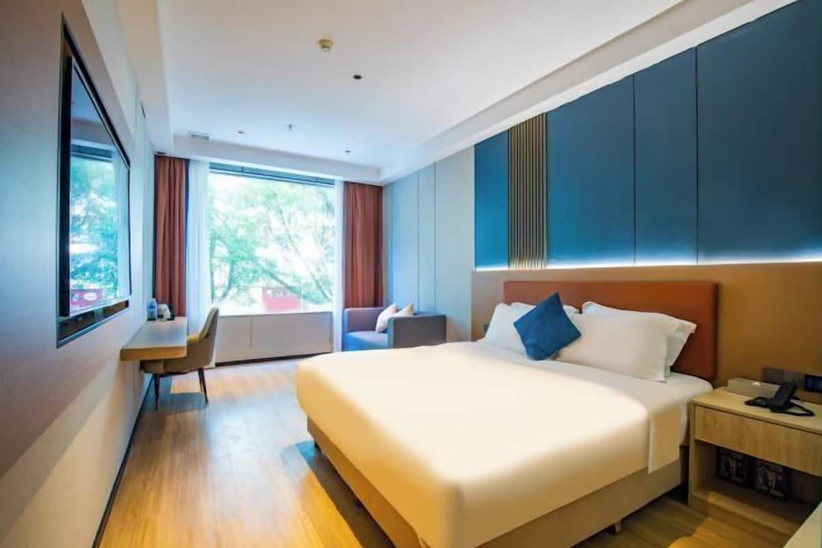 Une chambre d’hôtel moderne avec un grand lit, un bureau et une vue sur la verdure.