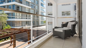 Ein Balkon mit Korbmöbeln und einer Holz-Pergola.