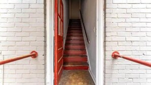 A staircase with white brick walls and red handrails leading to a door. - Eclectic Escape #4 - Team Joseph Ellen (Jacksonville)