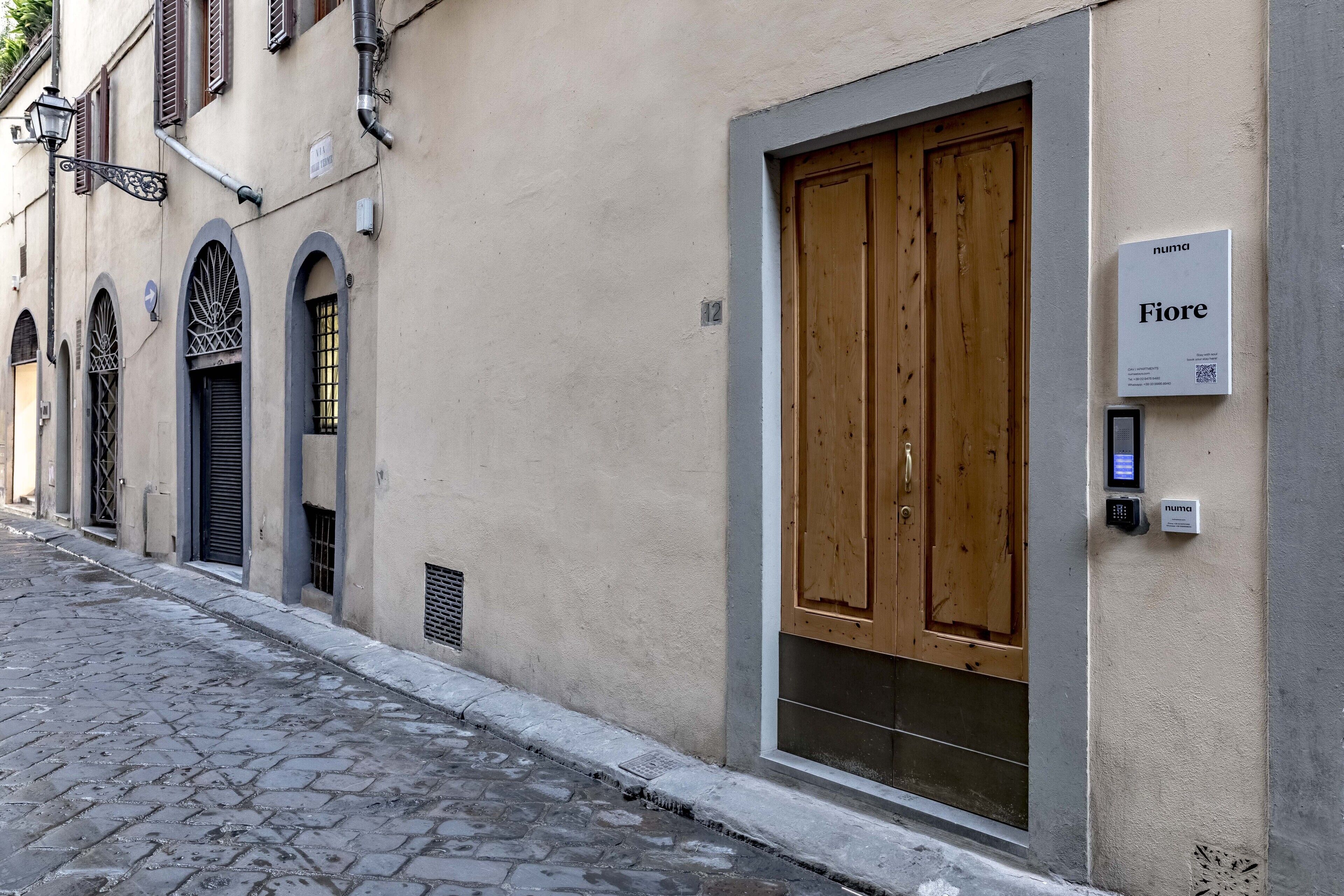 A building with a large wooden door, a sign reading "Fiori," and a keypad lock.